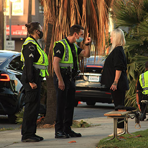 Police officers speaking with a woman on a sidewalk, representing a roadside DUI stop.